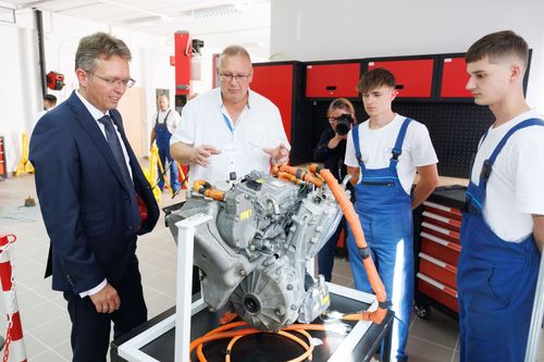 Hankó Balázs miniszter diákokkal egy motorblokk előtt